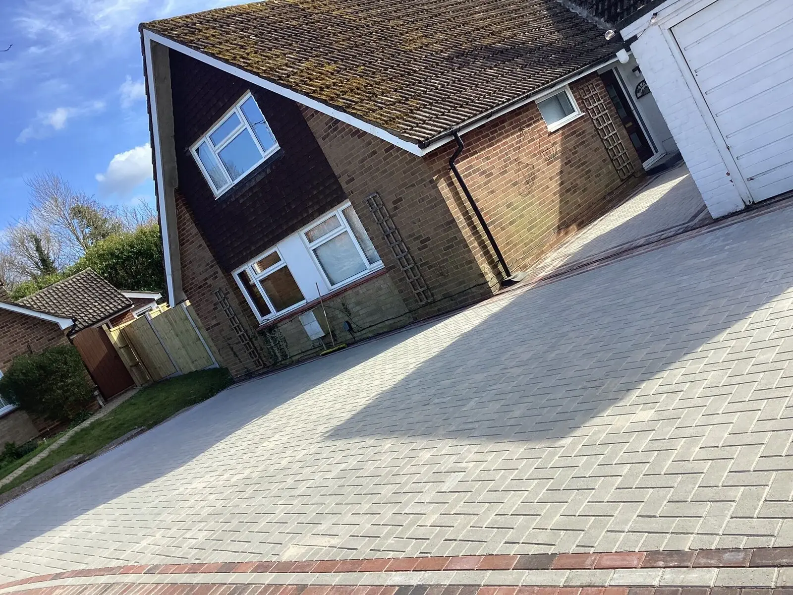 Block-paved driveway with a contrasting brick border, sweeping up to a garage