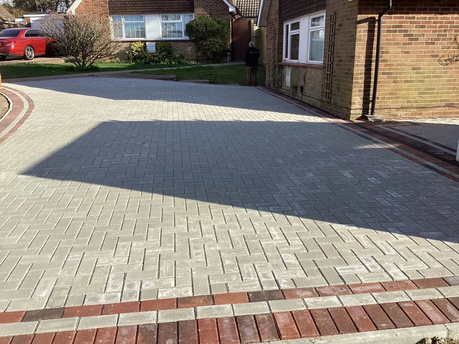 Block-paved driveway with decorative brick banding, laid across a full front garden