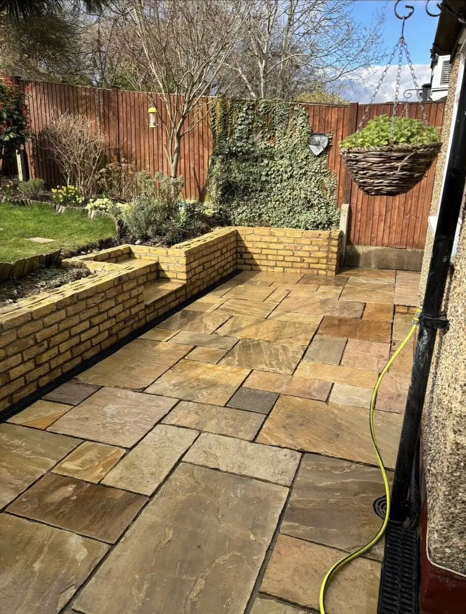 Sandstone patio bordered by raised brick planting beds
