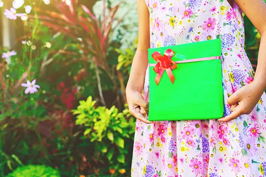 A Gregory's Gardens client holding a gift in a planted garden